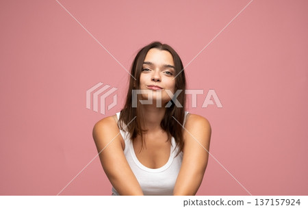 Young woman showing confident smirk, looking at camera with playful facial expression on pink background Young woman showing confident smirk, looking at camera with playful facial expression on pink background 137157924