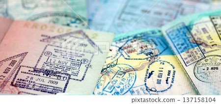 Big amount of passport pages full of colorful stamps after travel and border crossing. Tourism and border control concept. Immigration and travel around the world Big amount of passport pages full of colorful stamps after travel and border crossing. Tourism and border control concept. Immigration and travel around the world 137158104
