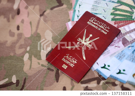 Omani passport on table and money. Official identification document book for citizens of Oman. Concept of travel and tourism 137158311