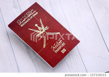 Omani passport on table close up. Official identification document book for citizens of Oman. Concept of travel and tourism Omani passport on table close up. Official identification document book for citizens of Oman. Concept of travel and tourism 137158315