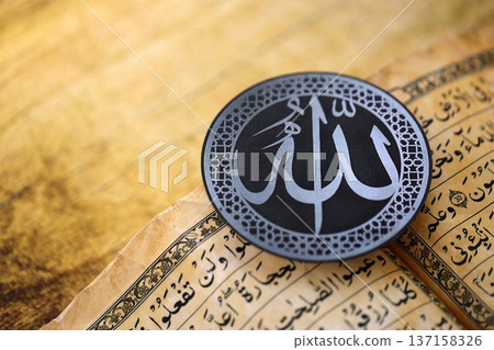 Sign with Islam inscription on Muslim holy book in mosque. Details of arabic calligraphy on sticker. Concept of Islam religion and praying in arabic countries Sign with Islam inscription on Muslim holy book in mosque. Details of arabic calligraphy on sticker. Concept of Islam religion and praying in arabic countries 137158326