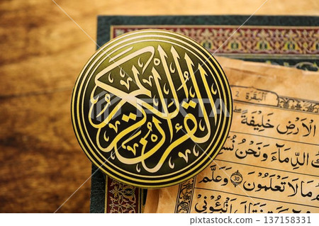 Sign with Al Quran inscription on Muslim holy book in mosque. Details of arabic calligraphy on sticker. Concept of Islam religion and praying in arabic countries Sign with Al Quran inscription on Muslim holy book in mosque. Details of arabic calligraphy on sticker. Concept of Islam religion and praying in arabic countries 137158331