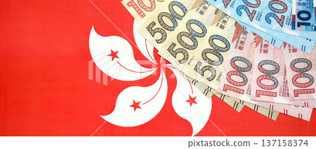 Big pile of Hong Kong dollars money bills banknotes on red flag. Lots of money of Chinese Hong Kong HKD currency cash. Economics and business in HongKong 137158374