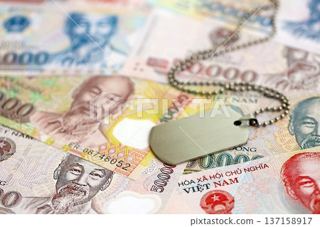 Vietnamese dong currency money bills and military token close up. The concept of army service Vietnamese dong currency money bills and military token close up. The concept of army service 137158917