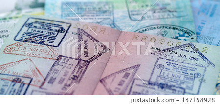 Big amount of passport pages full of colorful stamps after travel and border crossing. Tourism and border control concept. Immigration and travel around the world Big amount of passport pages full of colorful stamps after travel and border crossing. Tourism and border control concept. Immigration and travel around the world 137158928