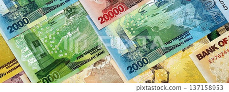 Ugandan shilling paper banknotes pile on table. Uganda UGX currency money bills in big amount. Concept of economics, taxation and banking in Uganda Ugandan shilling paper banknotes pile on table. Uganda UGX currency money bills in big amount. Concept of economics, taxation and banking in Uganda 137158953