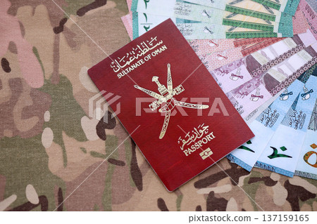 Omani passport on table and money. Official identification document book for citizens of Oman. Concept of travel and tourism 137159165