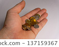 Coins are held in an open palm with various denominations and colors during a currency count at a home setting 137159367