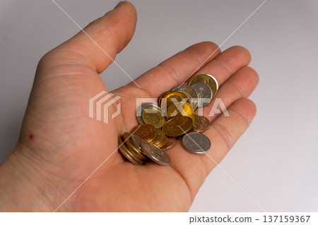 Coins are held in an open palm with various denominations and colors during a currency count at a home setting 137159367