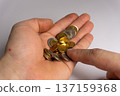Hand holding assorted coins with a focus on money and currency at home during daytime 137159368