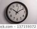 Clock shows the time in a simple design on a white wall with clear numbers and hands indicating the hour and minutes 137159372