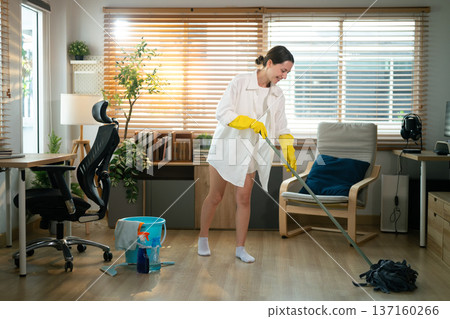Woman Mopping Floor in Home Office During Cleaning Routine 137160266