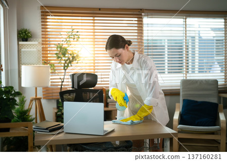 Woman cleaning home office desk with disinfectant spray 137160281