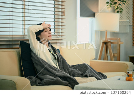 Young asian woman with headache or migraine sitting on sofa Young asian woman with headache or migraine sitting on sofa 137160294