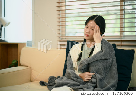Young asian woman with headache or migraine sitting on sofa 137160300
