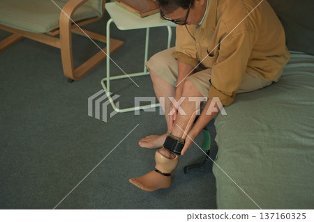 Middle aged man adjusting a prosthetic leg at home Middle aged man adjusting a prosthetic leg at home 137160325