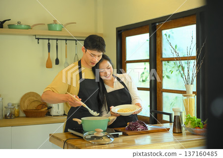 Young couple cooking spaghetti in a cozy kitchen. People, food and domestic life concept 137160485