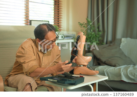 Middle aged man repairing a prosthetic leg at home with a screwdriver, focused self care and independence during disability adaptation 137160489