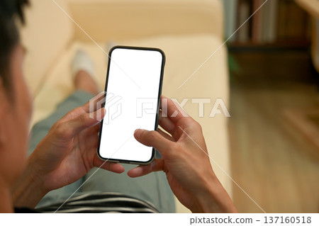 Man using smartphone blank screen modern design while lying on the sofa in living room 137160518