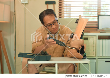 Middle aged man repairing a prosthetic leg at home with a screwdriver, focused self care and independence during disability adaptation 137160526