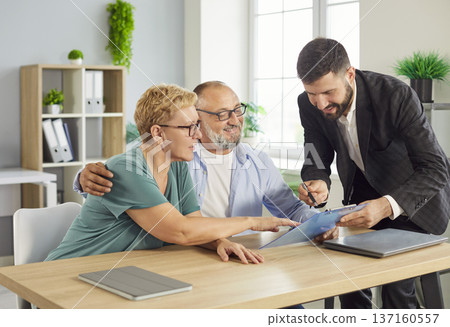 Senior couple meets friendly financial advisor to review documents in office 137160557