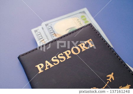 Passport in leather cover with dollar banknotes on blue background, travel finance and international journey concept closeup Passport in leather cover with dollar banknotes on blue background, travel finance and international journey concept closeup 137161248