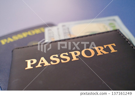 Passport in leather cover with dollar banknotes on blue background, travel finance and international journey concept closeup Passport in leather cover with dollar banknotes on blue background, travel finance and international journey concept closeup 137161249
