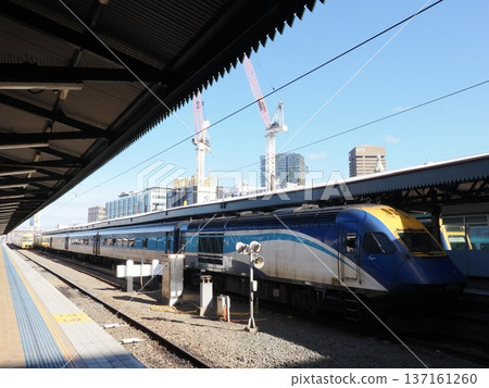 A blue and yellow train running through the city - a futuristic feel permeates the station platform A blue and yellow train running through the city - a futuristic feel permeates the station platform 137161260