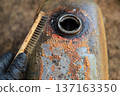 Hand using Wire Brush for cleaning old color on tank oil of motorcycle 137163350