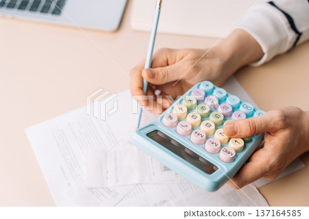 Person calculating expenses with pastel calculator and pen on papers, tax and budget planning 137164585