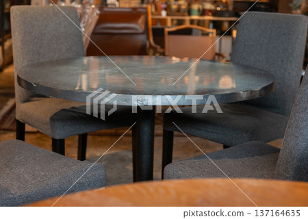 咖啡廳的圓桌和灰色椅子。現代風格的室內設計,採用柔和的色調,搭配一組圓桌椅。 咖啡廳的圓桌和灰色椅子。現代風格的室內設計,採用柔和的色調,搭配一組圓桌椅。 137164635