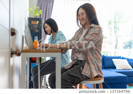 Work from Home: Two women engrossed in remote work, their focused expressions mirroring the productivity and flexibility of a modern, adaptable workplace. Work from Home: Two women engrossed in remote work, their focused expressions mirroring the productivity and flexibility of a modern, adaptable workplace. 137164799