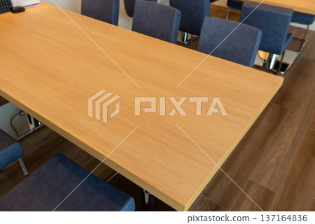 Spacious wooden conference table and blue chairs in a meeting room in an office or coworking space 137164836