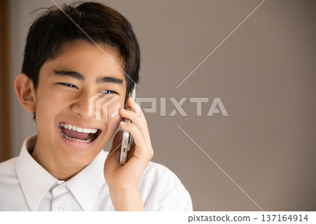 面帶微笑的學生正在用智慧型手機通話 面帶微笑的學生正在用智慧型手機通話 137164914