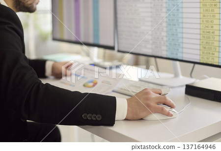 Accountant analyzing invoices on computer with spreadsheets and charts at office Accountant analyzing invoices on computer with spreadsheets and charts at office 137164946