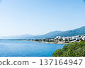 Clear blue sea and buildings lining the coastline under bright sunlight on the French island of Corsica in the Mediterranean Sea 137164947