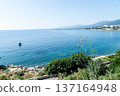 Clear blue sea and buildings lining the coastline under bright sunlight on the French island of Corsica in the Mediterranean Sea 137164948