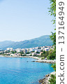Clear blue sea and buildings lining the coastline under bright sunlight on the French island of Corsica in the Mediterranean Sea 137164949