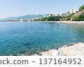 Clear blue sea and buildings lining the coastline under bright sunlight on the French island of Corsica in the Mediterranean Sea 137164952
