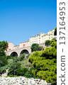 An apartment building on a hill surrounded by greenery under a bright, clear sky on the French island of Corsica in the Mediterranean Sea 137164953