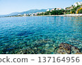 Clear blue sea and buildings lining the coastline under bright sunlight on the French island of Corsica in the Mediterranean Sea 137164956