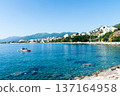 Clear blue sea and buildings lining the coastline under bright sunlight on the French island of Corsica in the Mediterranean Sea 137164958