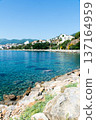 Clear blue sea and buildings lining the coastline under bright sunlight on the French island of Corsica in the Mediterranean Sea 137164959