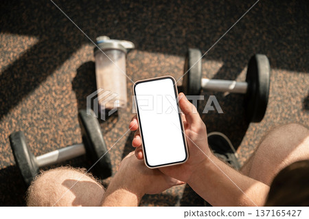 Man checking smartphone after workout in gym Man checking smartphone after workout in gym 137165427