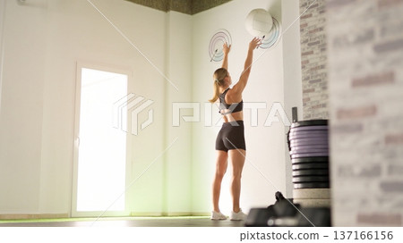 Woman performing wall ball exercise at fitness gym 137166156