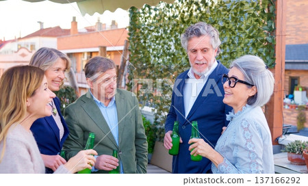 Friends socializing, drinking beer together on a rooftop party Friends socializing, drinking beer together on a rooftop party 137166292