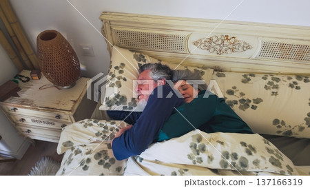 Senior couple sleeping together in bed hugging Senior couple sleeping together in bed hugging 137166319