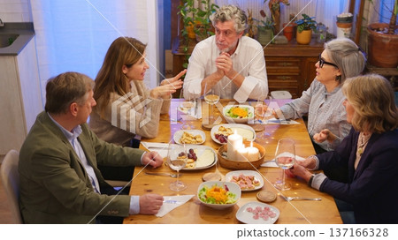 Group of friends talking during dinner party at home Group of friends talking during dinner party at home 137166328