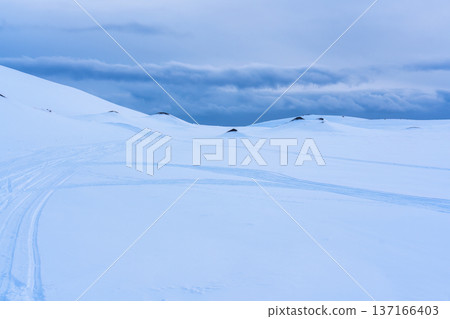 White glacier mountain with snowmobile track on summit in winter 137166403