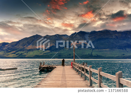 Scenic sunset sky over mountain in Lake Wakatipu and couple embracing in Glenorchy, New Zealand Scenic sunset sky over mountain in Lake Wakatipu and couple embracing in Glenorchy, New Zealand 137166588